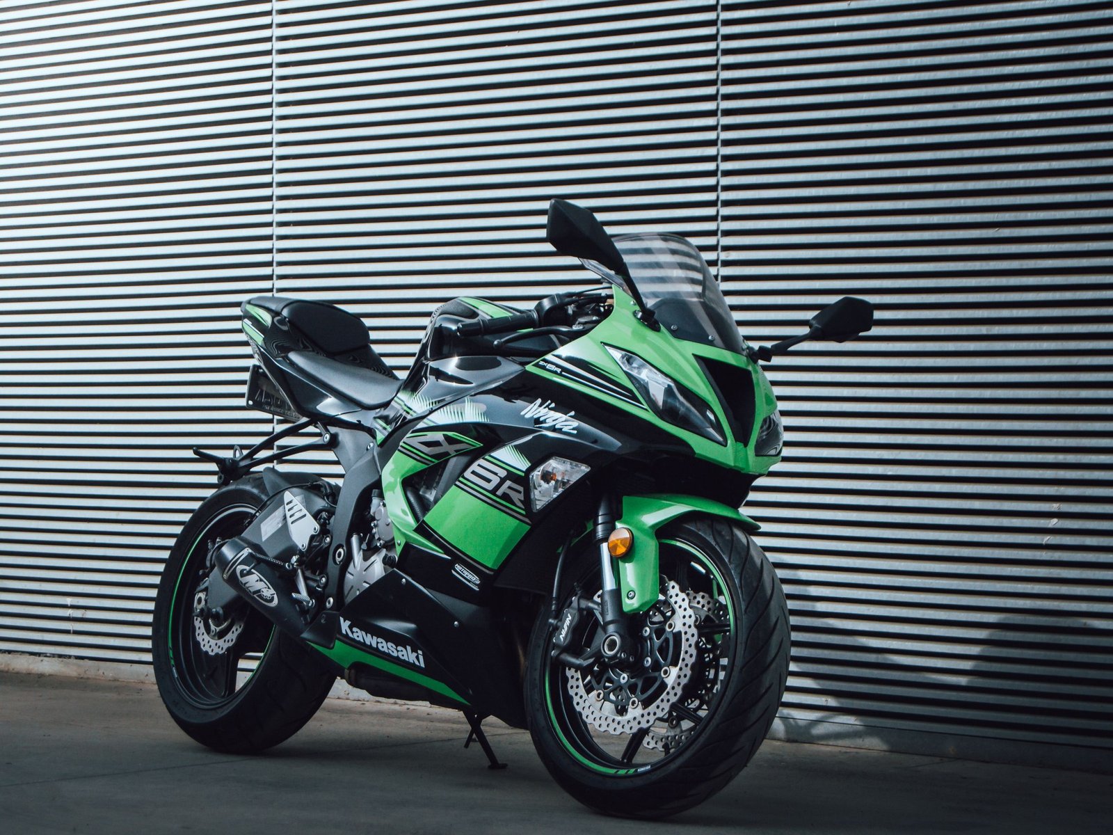 Kawasaki Ninja H2 noire et verte exposée dans un garage, gros plan sur le carénage et l'échappement.
